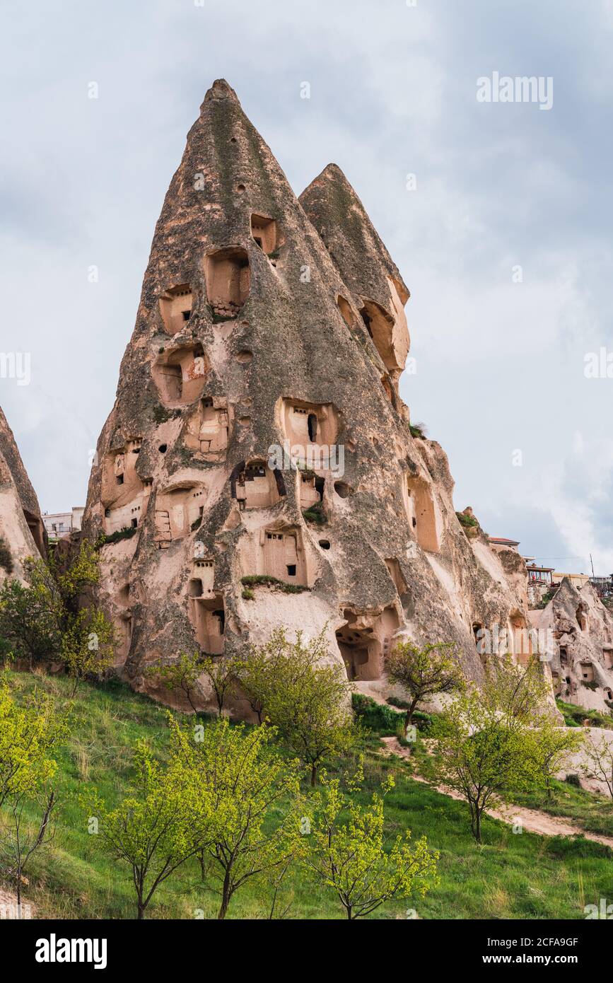 Rock houses of old city located on rough mountain against cloudy sky of Cappadocia, Turkey Stock Photo