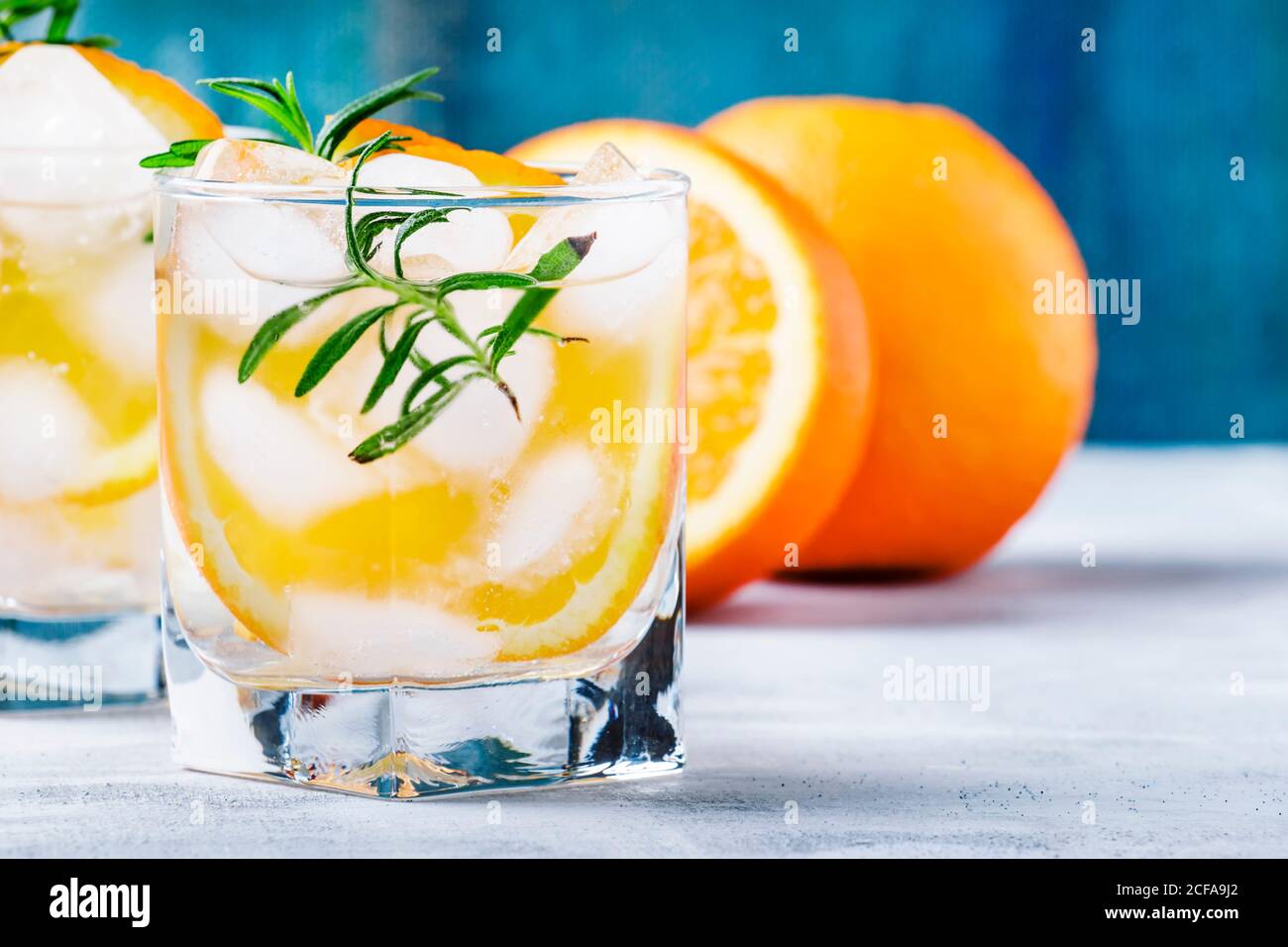Cold summer drink with mineral water, ice, orange and rosemary ...