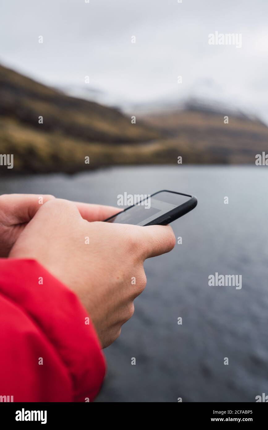 anonymous man using smartphone near a lake in Faroe Island Stock Photo
