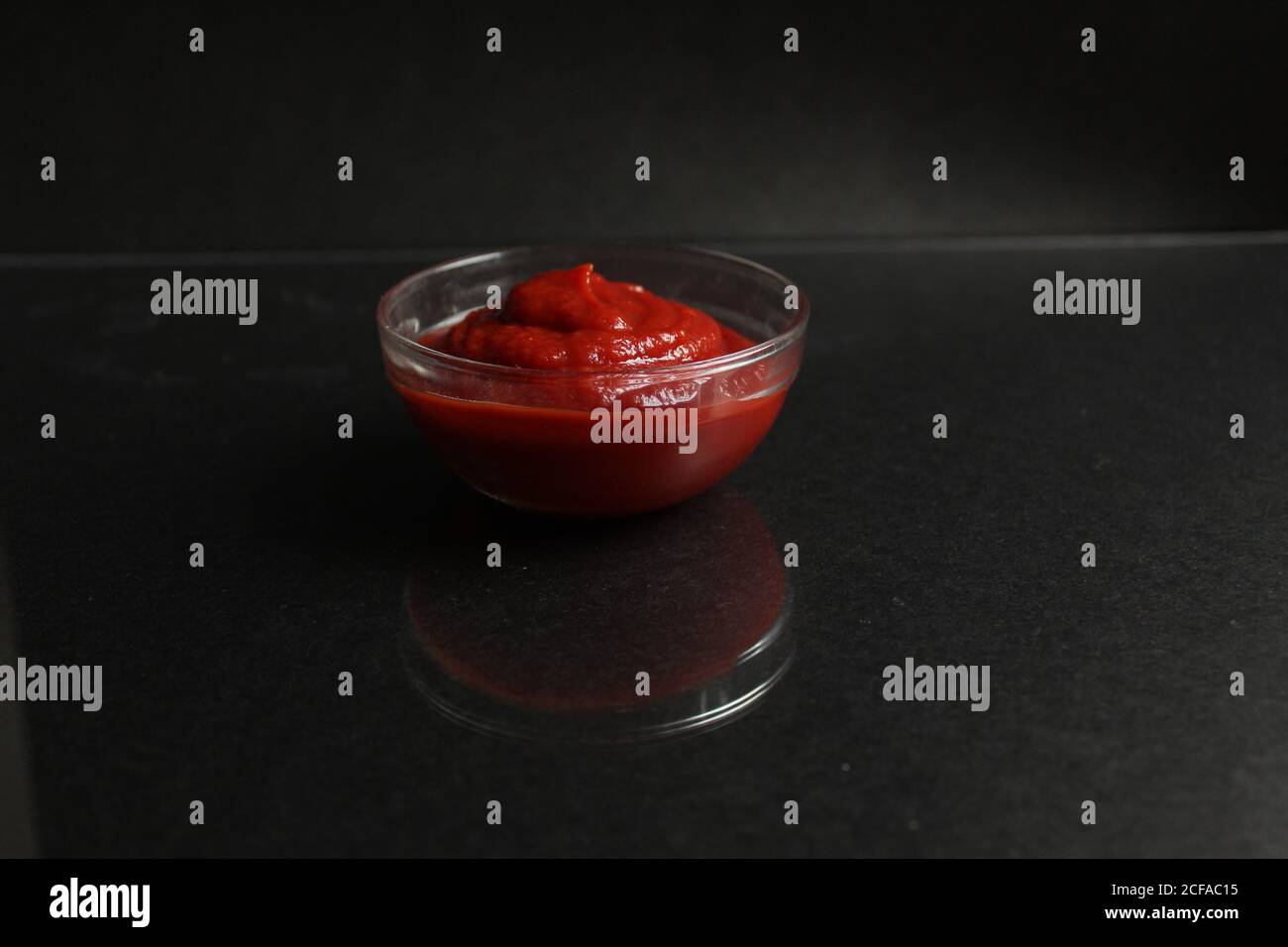 red tomato sauce in a glass bowl, a gravy boat on black background copy space Stock Photo