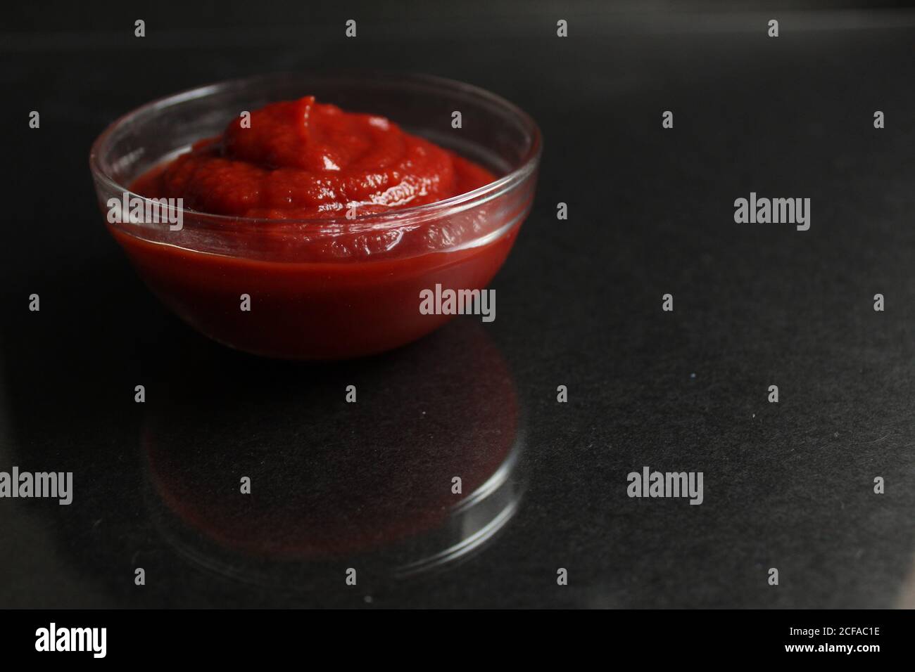 red tomato sauce in a glass bowl, a gravy boat on black background copy space Stock Photo