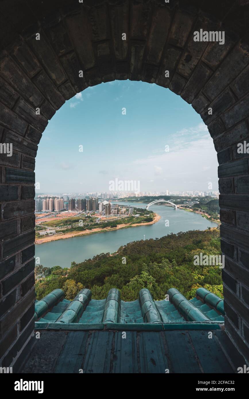 Shot through brick old window with view of cityscape of Nanning on river shore, China Stock Photo