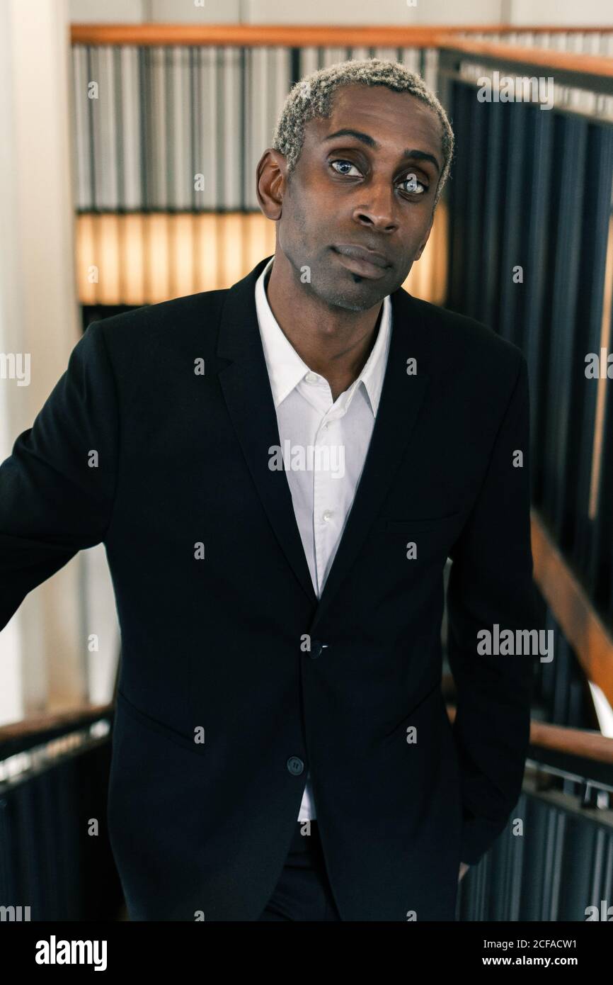 Confident black businessman leaning on railing Stock Photo - Alamy