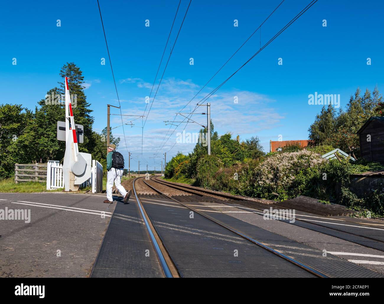 Man walking across East Coast mainline railway line level crossing