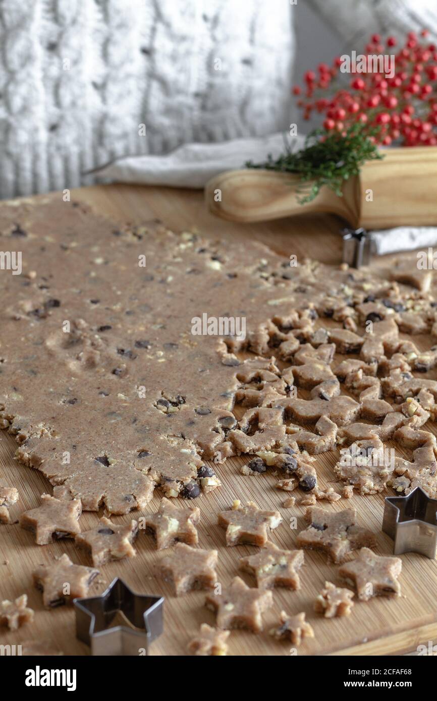 From above of brown rolled dough on table for cookies in shape of star in kitchen Stock Photo