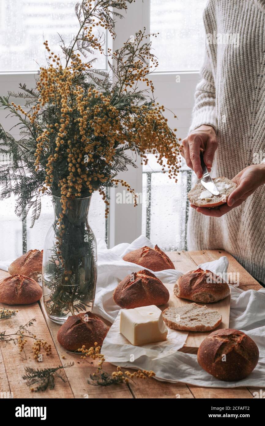 faceless lady spreading butter on bread in kitchen Stock Photo