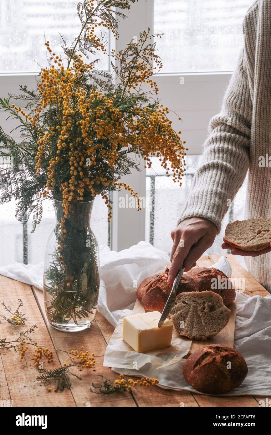 faceless lady spreading butter on bread in kitchen Stock Photo