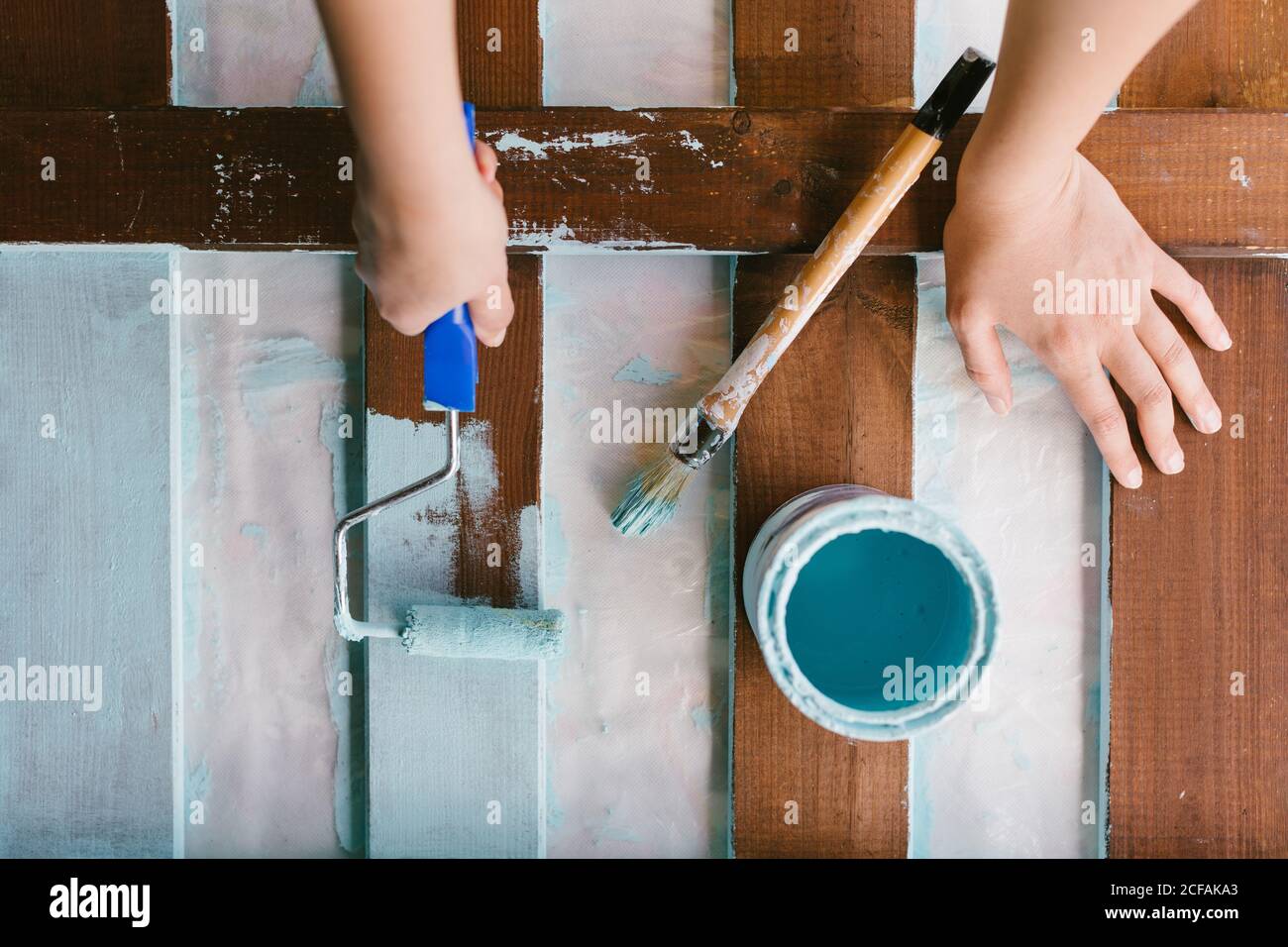 Top view of a caucasian's hands painting an old fence to be restored. Stock Photo