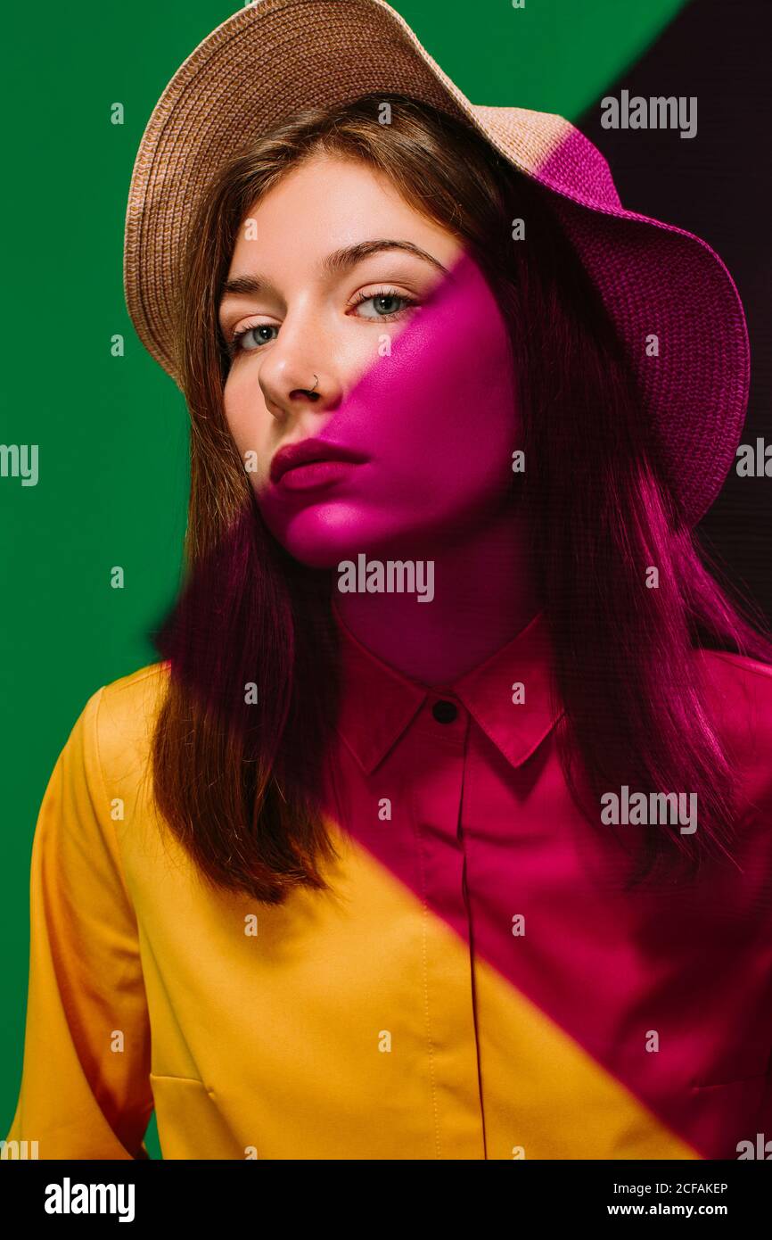 Young female model in stylish hat with red shadow on face and shoulder ...