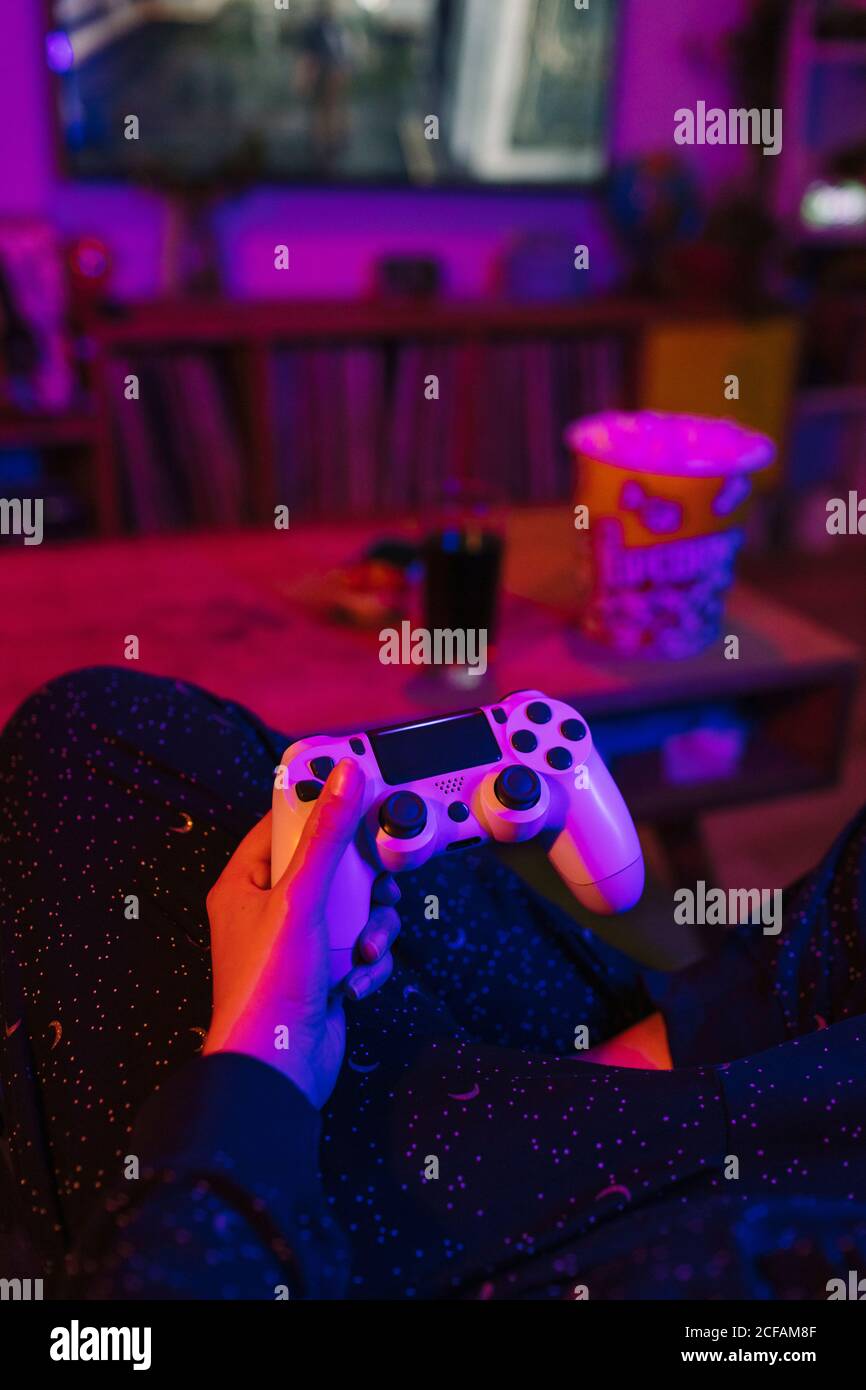 girl holding on a video game controller. She is in a living room at night  with pop-corns and cola drink during Corona lockdown. Behind view with  colorful lights Stock Photo - Alamy
