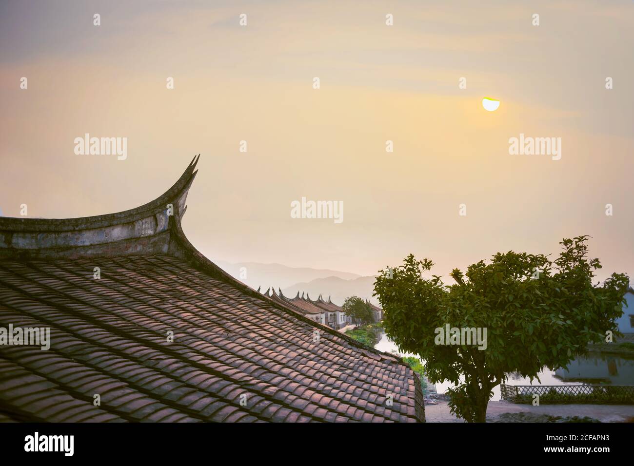 Aged stone houses with decorated roofs on background of cloudy sky in Daimei Village Stock Photo