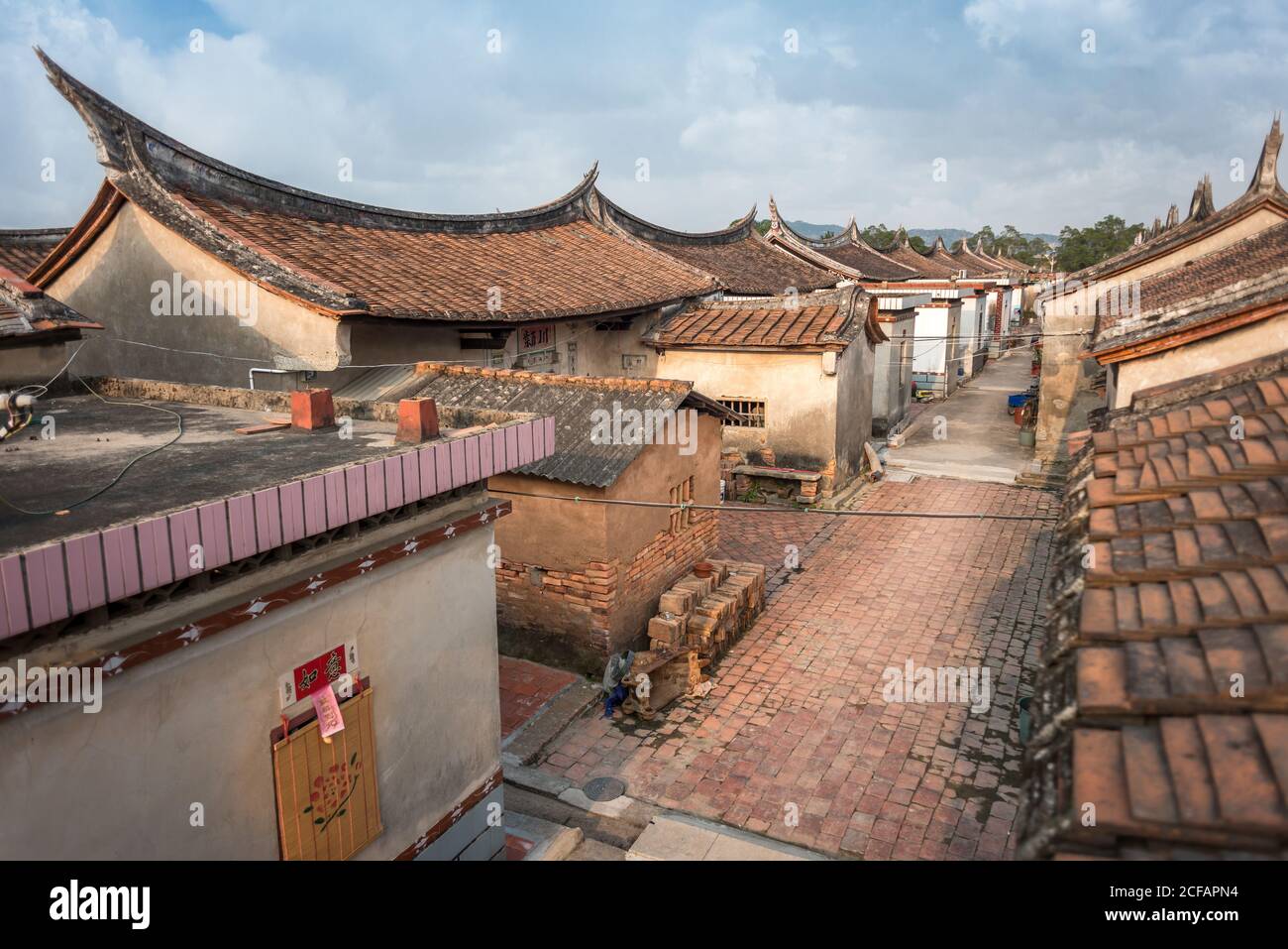 Narrow pathway surrounded by traditional stone buildings with ornamental  roofs in Daimei Village during sunrise Stock Photo - Alamy