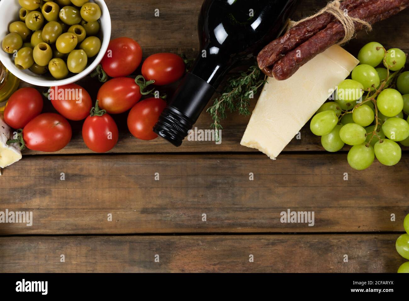 view of a composition with pieces of bread, cheese, sausage, fresh fruits and a bottle of wine on wo Stock Photo