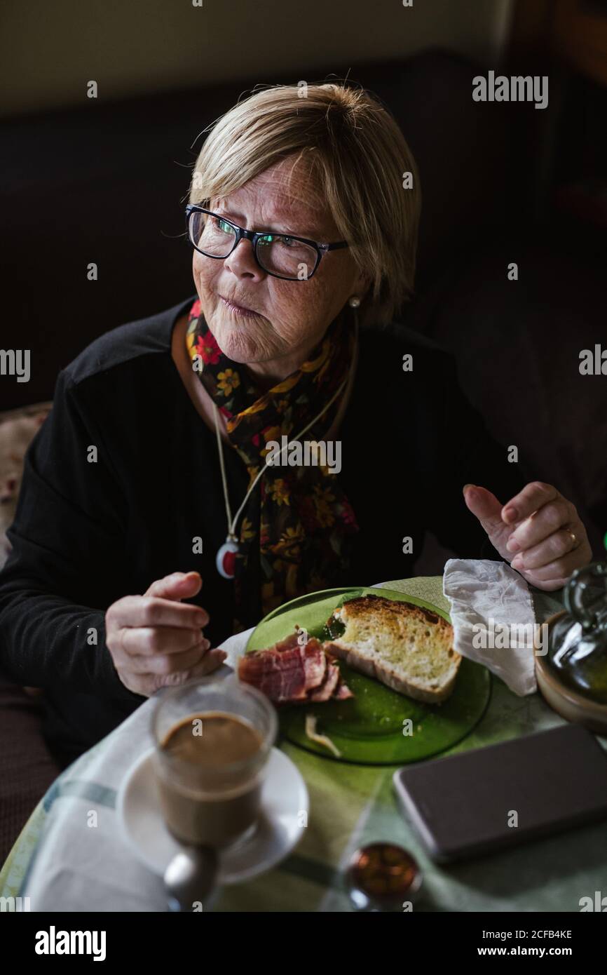 From above aged Woman having breakfast while sitting at table Stock Photo
