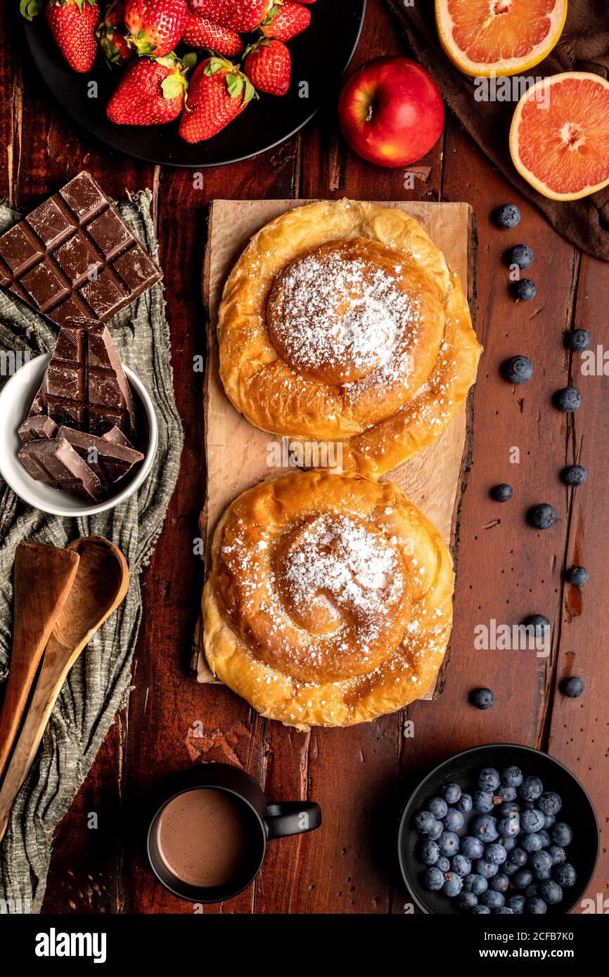 Fresh hot beverage and various tasty breakfast food placed on lumber tabletop in morning Stock