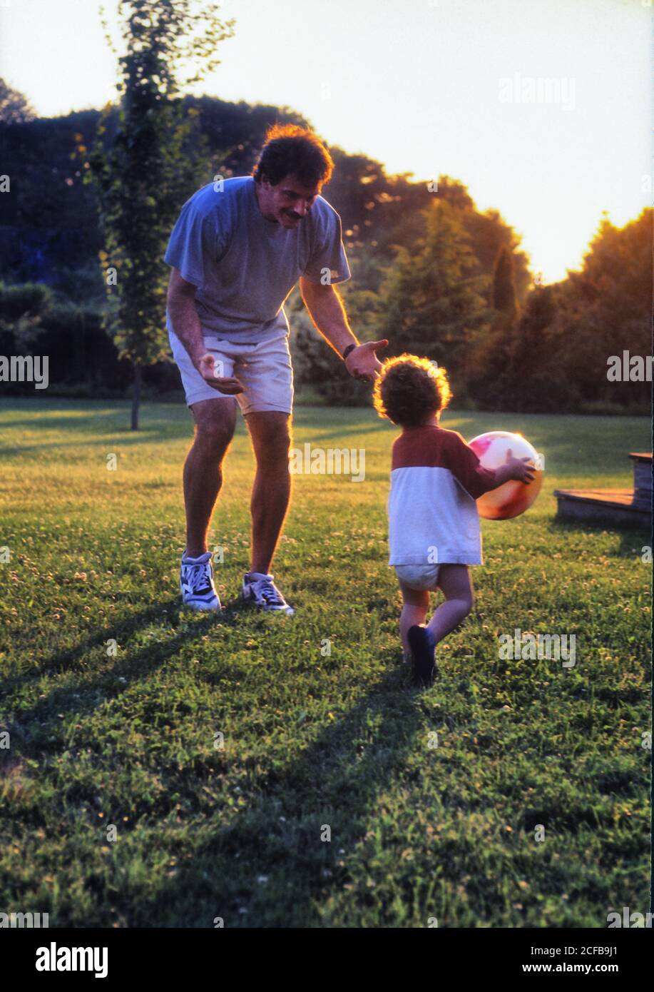 Boy Toddler playing on grass with Adult Stock Photo