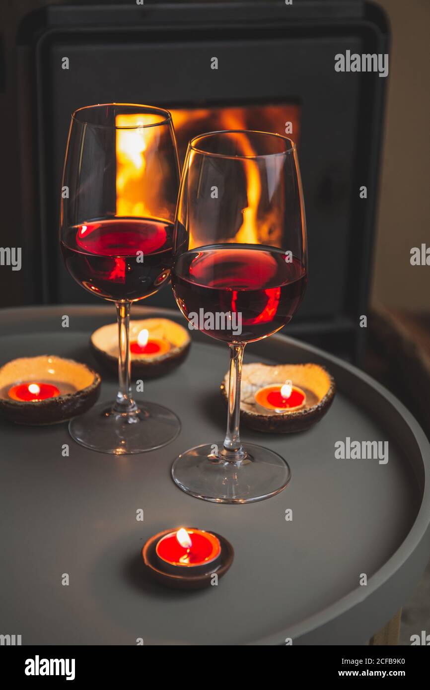 Two glasses of red wine front of fireplace. Romantic light Stock Photo
