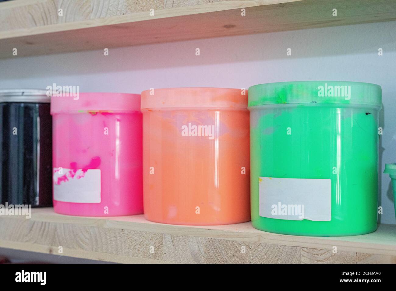 Shelves with colorful tins of paint of different shape size and colour
