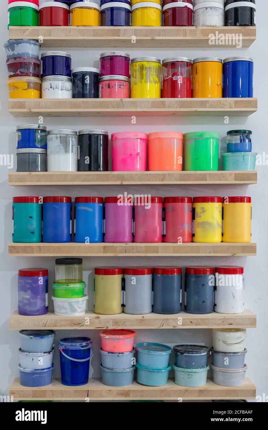 Shelves with colorful tins of paint of different shape size and colour
