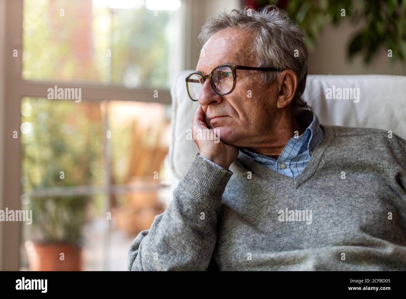 Senior man looking out of window at home Stock Photo