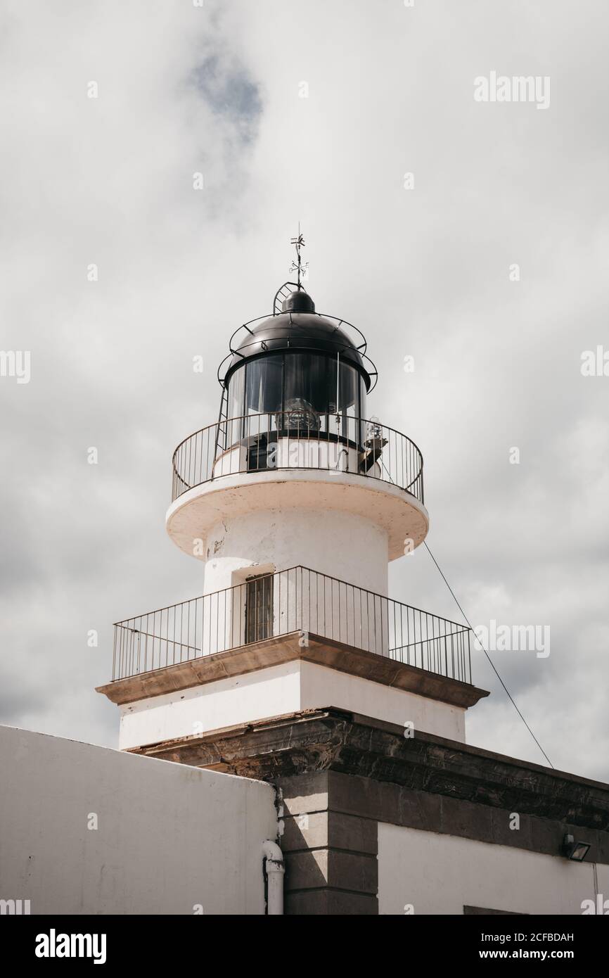 From below top of modern lighthouse building against sky on cloudy day ...