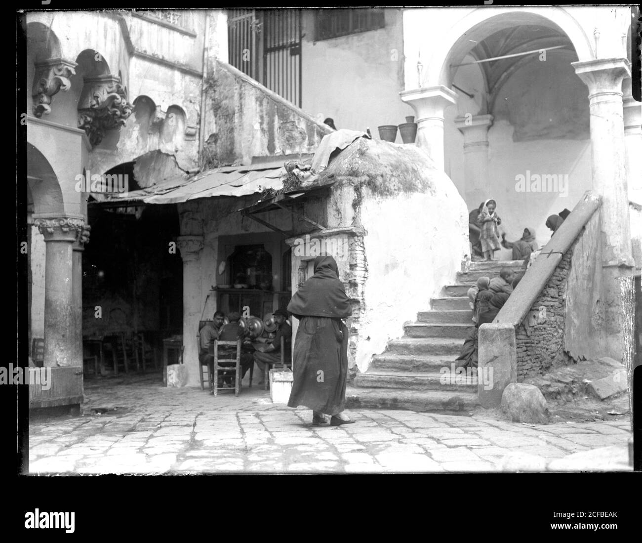Şadırvan Camii Konak in Smyrna / Izmir, Turkey. Three men sitting on chairs talking or playing, crowd of playing children. Photograph on dry glass plate from the Herry W. Schaefer collection, around 1910. Stock Photo