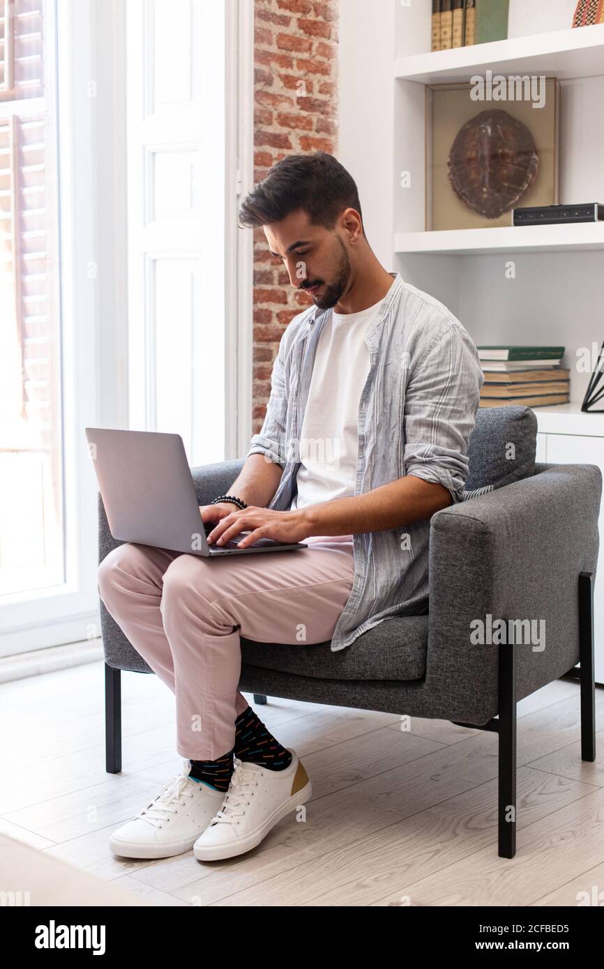 Bearded ethnic man using laptop while working on remote project at home Stock Photo