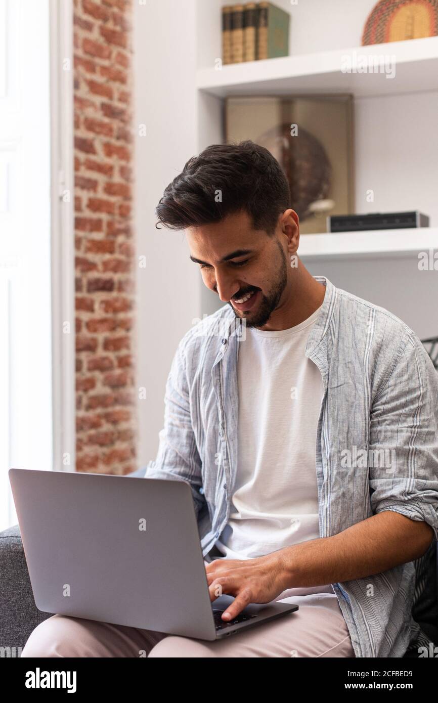 Bearded ethnic man using laptop while working on remote project at home Stock Photo