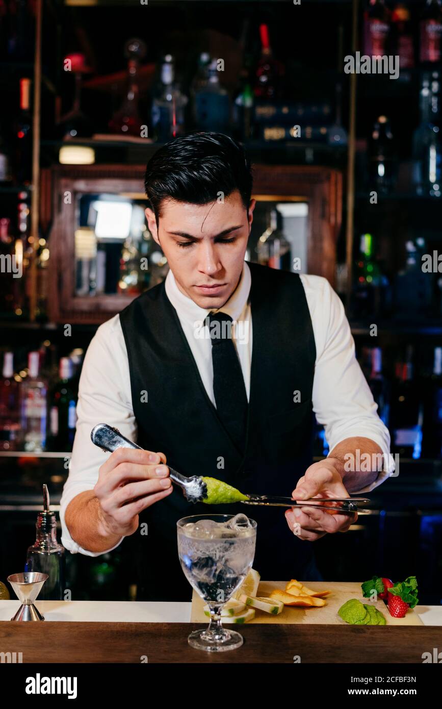 Young elegant barman working behind a bar counter mixing drinks with fruits  Stock Photo - Alamy