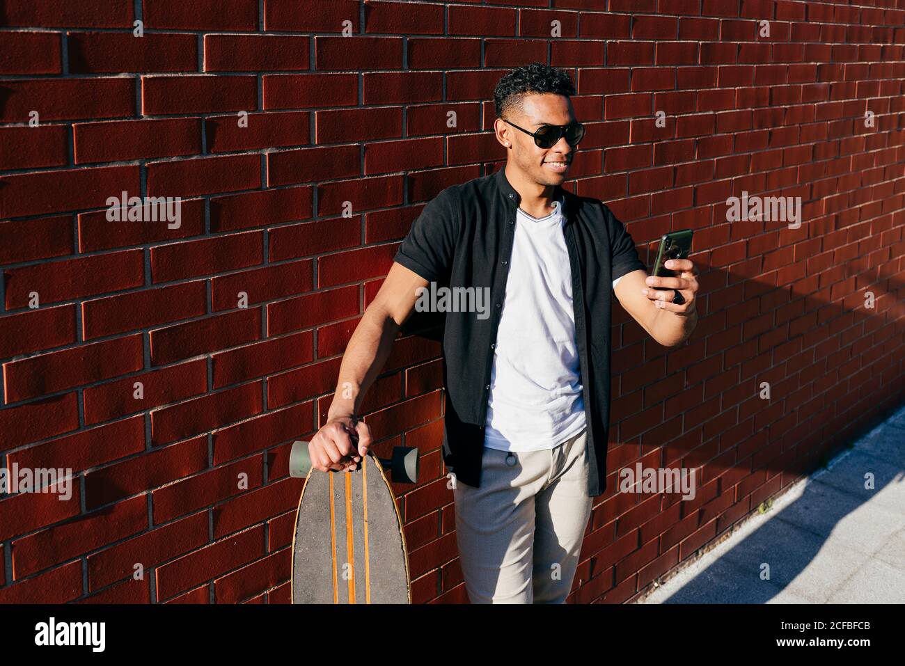 Young black male with long board speaking on phone Stock Photo