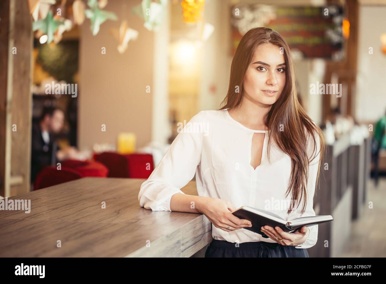 Portrait of smiling pretty young business woman in glasses sitting on ...