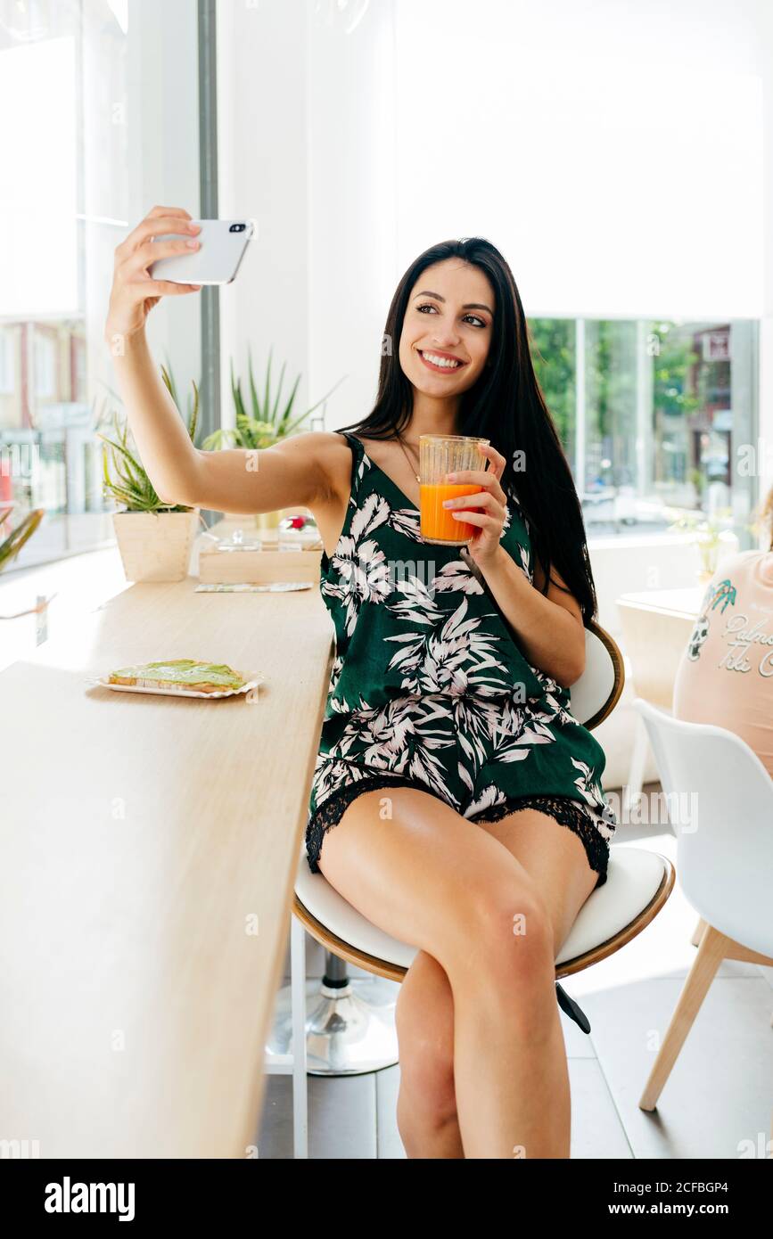 Lady with healthy drink taking selfie in cafe Stock Photo