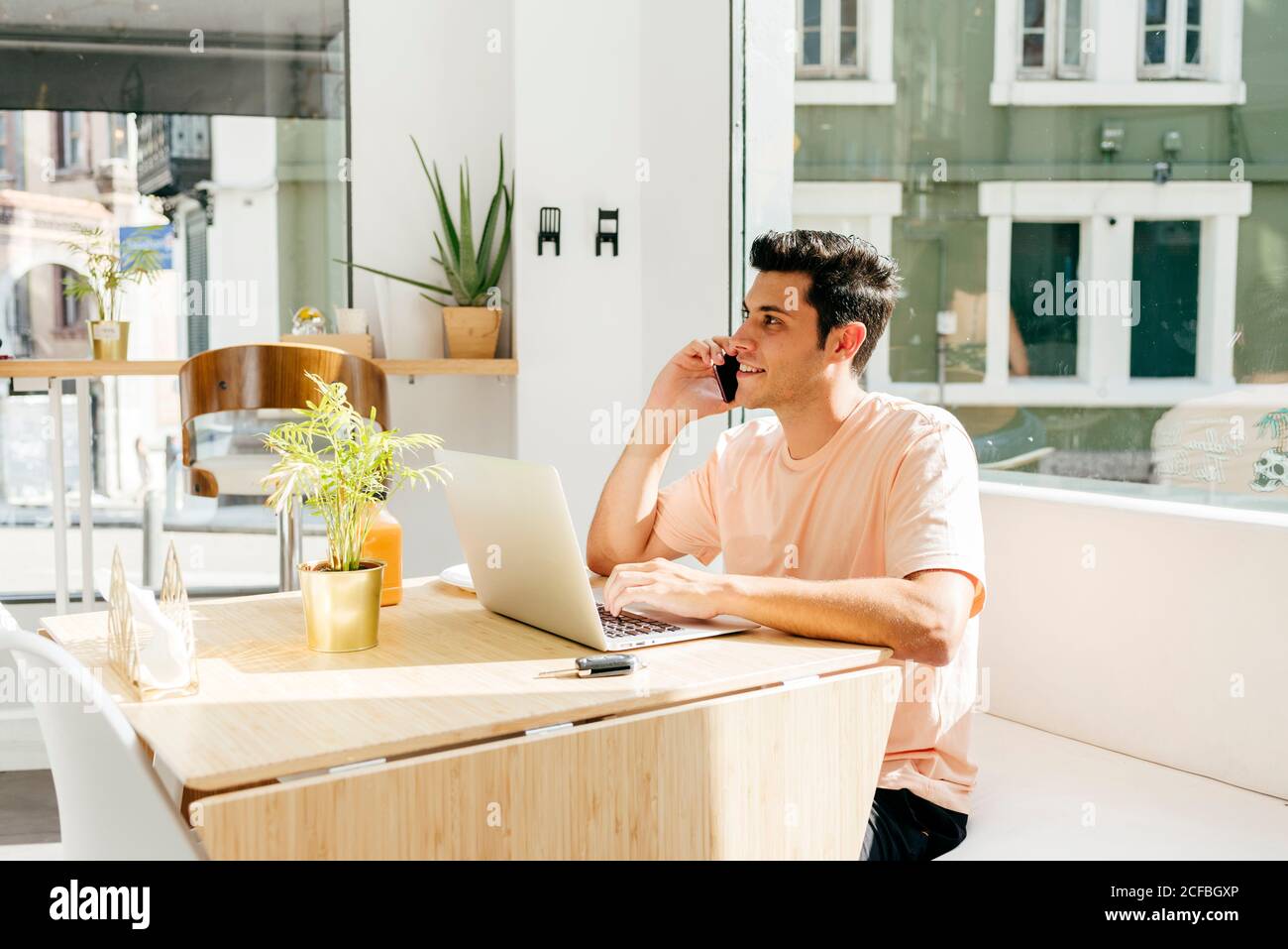 Crop man using laptop and talking phone in cafe Stock Photo