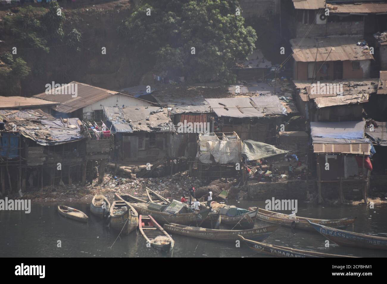 View from merchant port on shanty town in Freetown in Sierra Leone. Demolished and poor houses and wooden fishing boats in the suburb of capital. Stock Photo