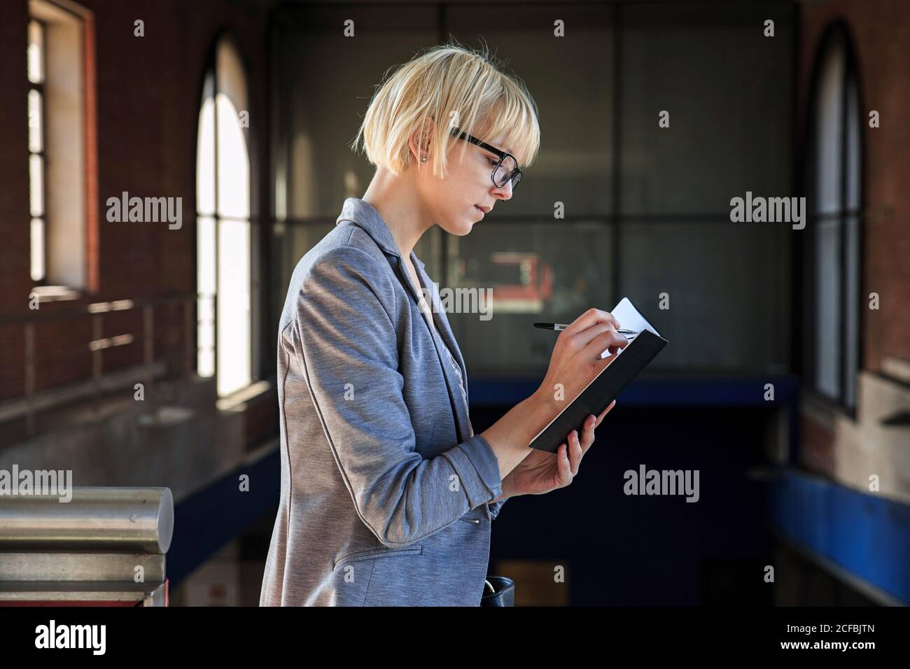 Side view of pretty businessWoman in formal clothes taking notes in notebook Stock Photo