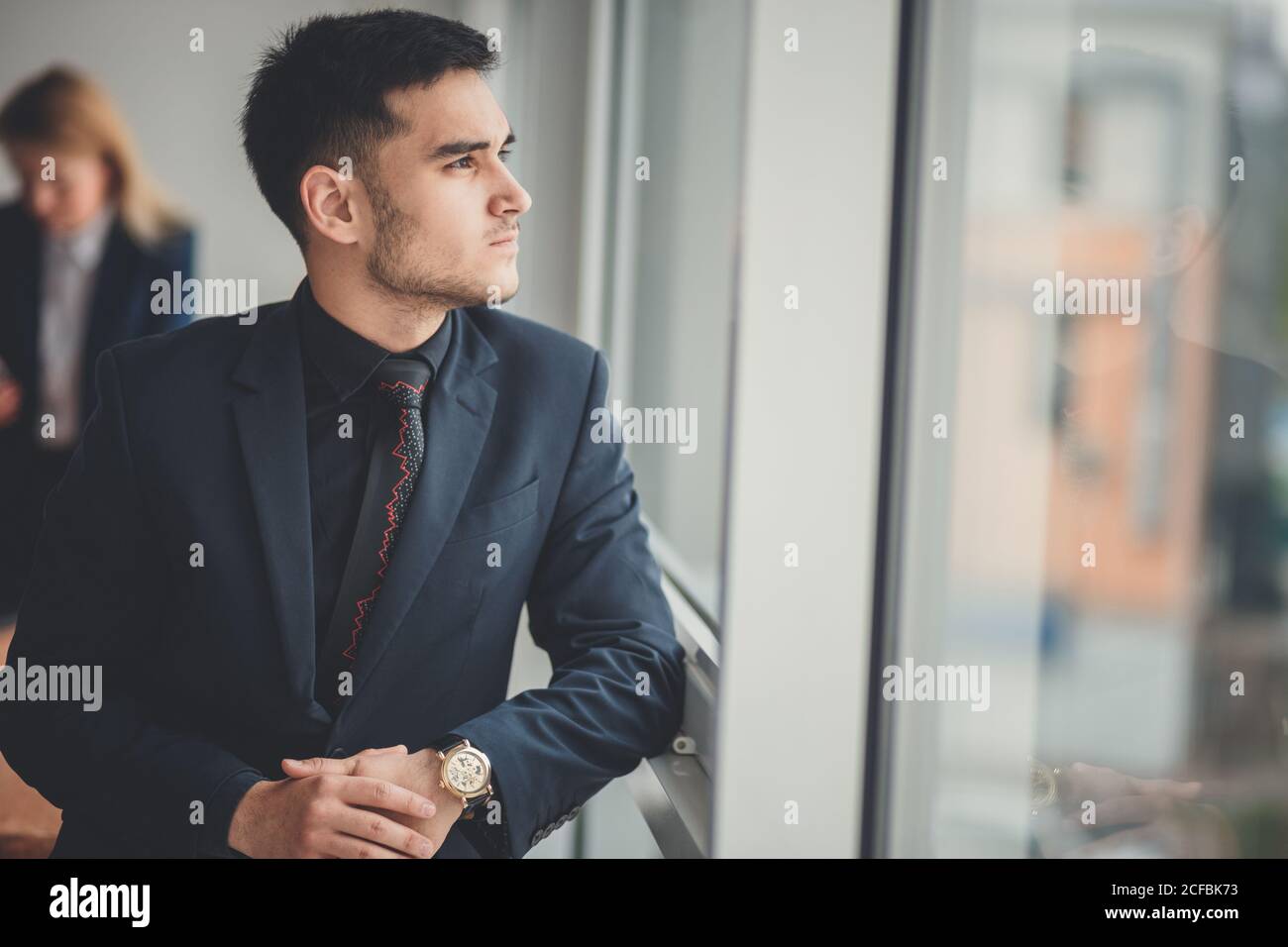 Successful attractive young businessman standing with arms crossed in ...