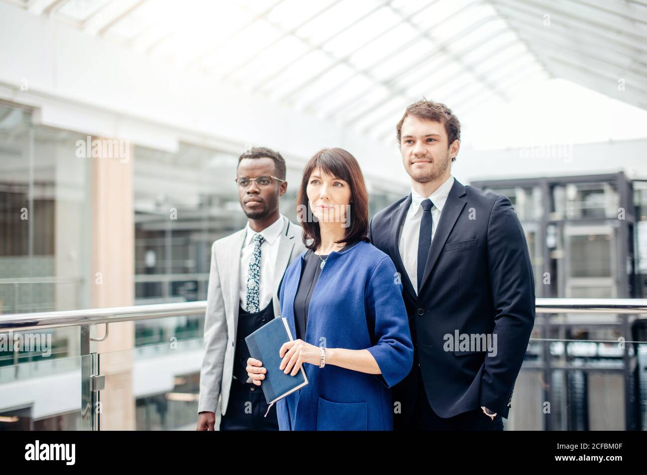 group of businesspeople standing together in office and looking at ...