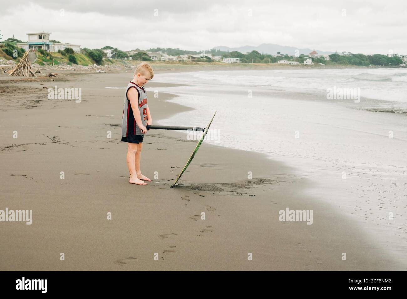 Young boy standing on the beach with his skim board Stock Photo