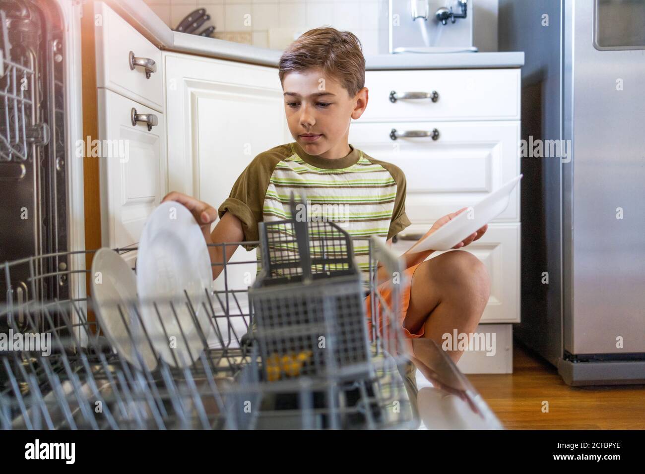 Little boy loading the dishwasher at home Stock Photo
