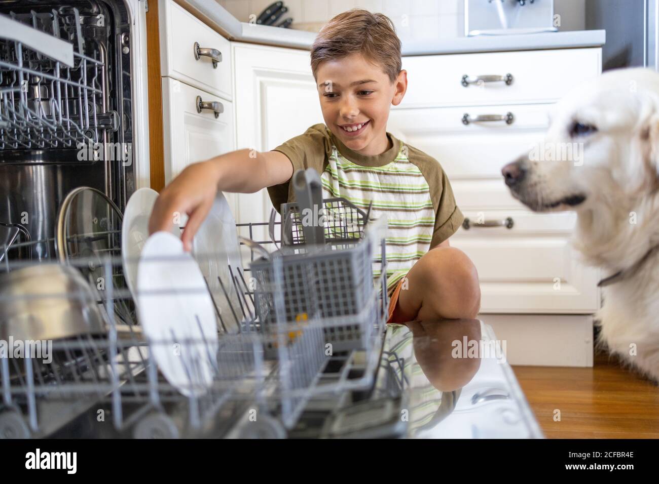 Little boy loading the dishwasher at home Stock Photo