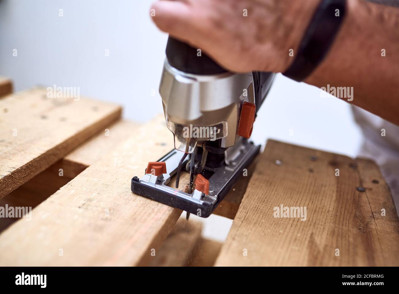 Hands of a young man cutting wooden pallets with a jigsaw. concept work