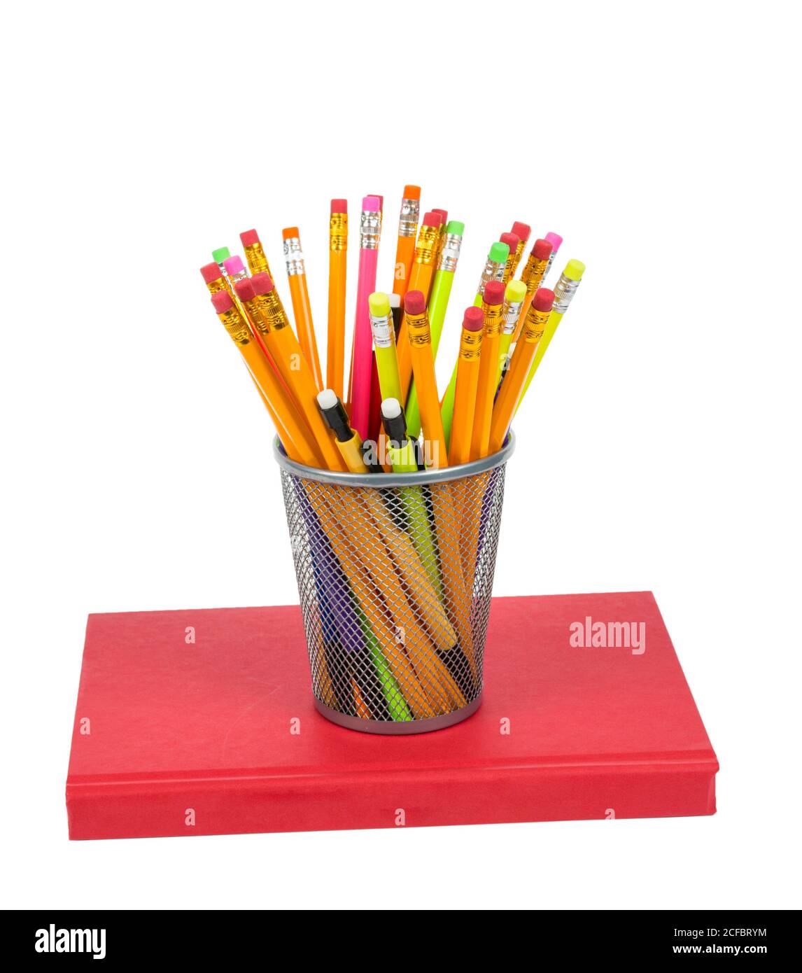 Isolated on white shot of a bunch of colorful pencils in a holder resting on a red book. Stock Photo