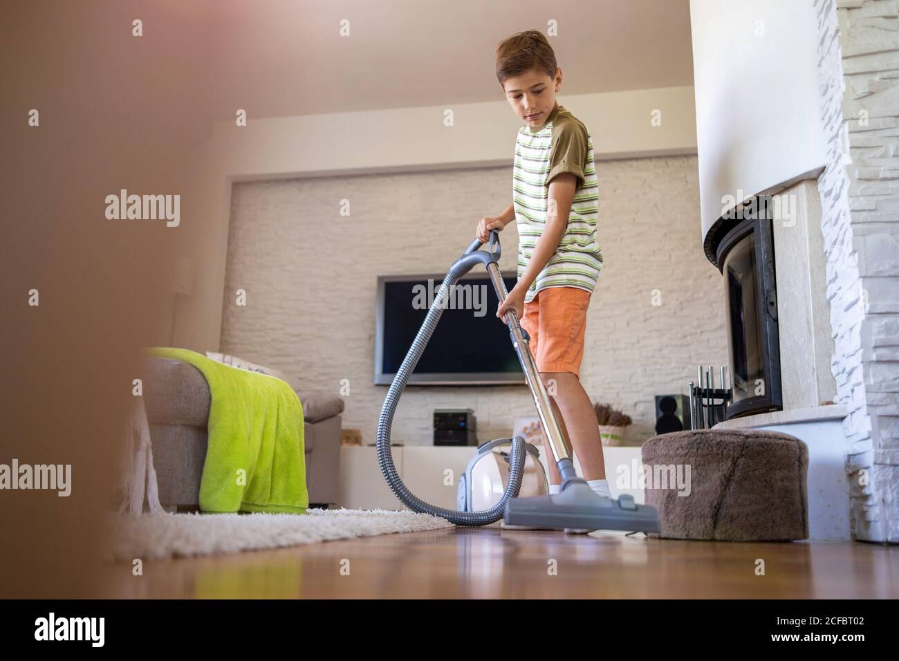 Boy vacuuming floor at home Stock Photo