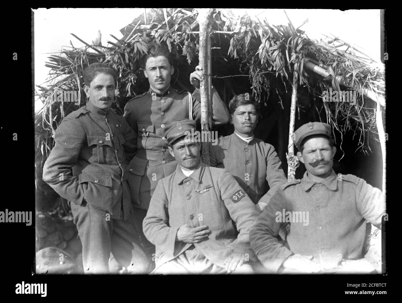 Group of greek soldiers in Turkey near Izmir / Smyrna with their camouflaged shelter at around 1910. One of the men is wearing a Phi Sigma Kappa emblem on his uniform sleeve. Photograph on dry glass plate from the Herry W. Schaefer collection, around 1910. Stock Photo