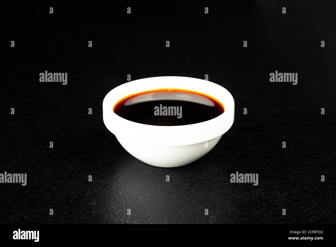 Soy sauce in a white saucer on a black background. For the restaurant