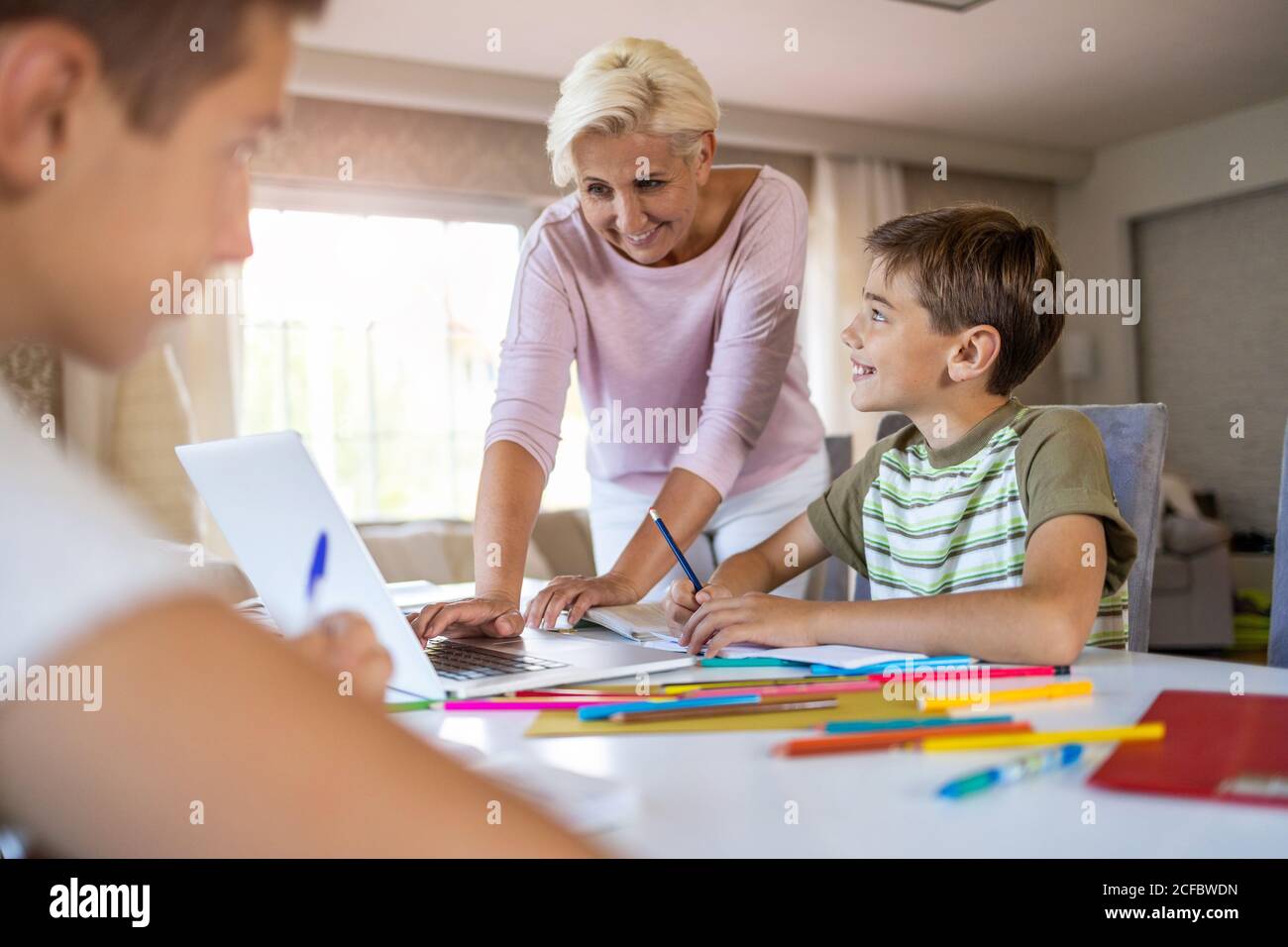 Mother helping her kids doing homework at home Stock Photo