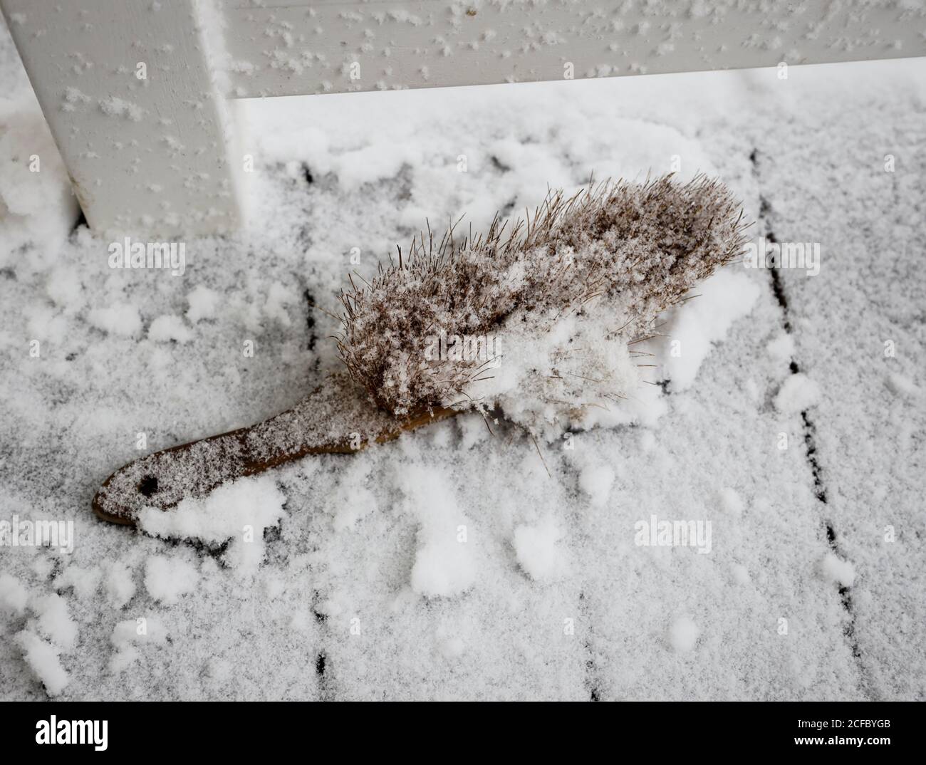 Hand broom in the snow on porch Stock Photo