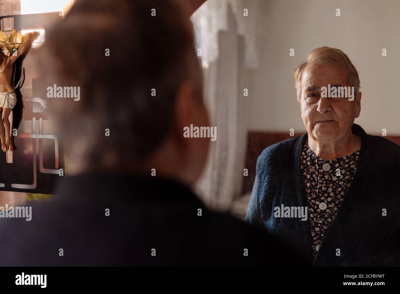 Elderly person looking in the mirror of his house Stock Photo
