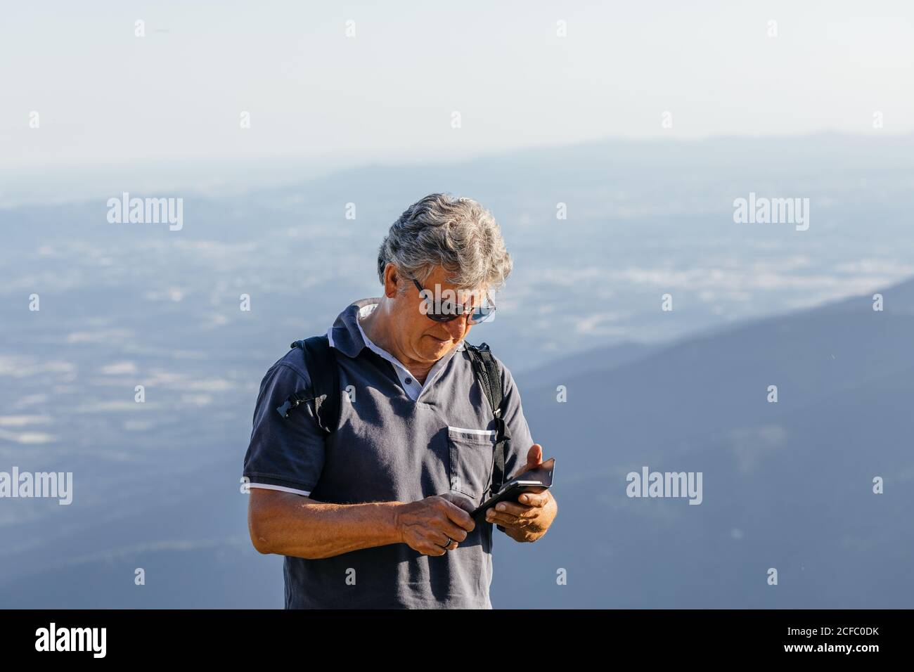 Senior man using his mobile phone on the mountain Stock Photo