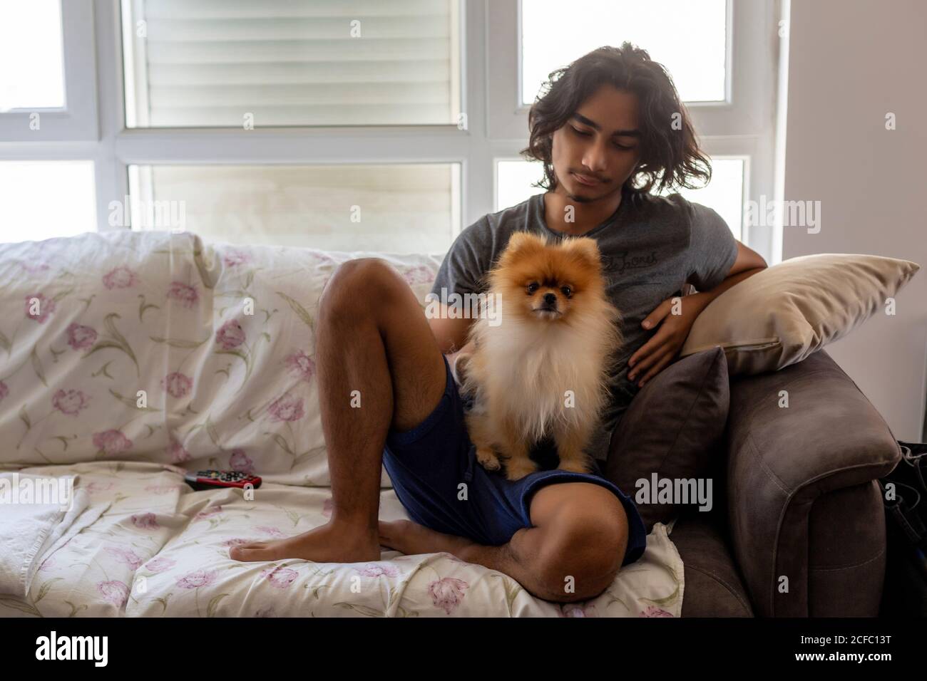 Teenager sitting at home with Pomerian dog Stock Photo